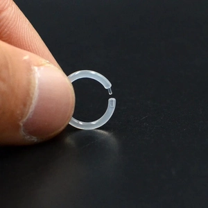 Macro view of transparent acrylic nose ring retainer held by hand on dark background