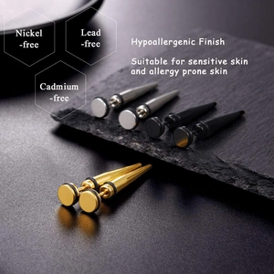 Détail macro de clous d'oreilles coniques en acier inoxydable argent, doré et noir poli