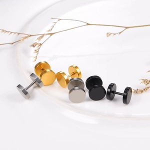 Boucles d'oreilles haltères rondes en or argent et noir sur une assiette blanche