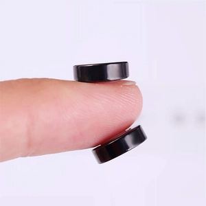 Détail de boucles d'oreilles magnétiques noires montrées sur un doigt pour la taille