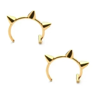 Macro detail of gold-finished punk style ear cuffs with three sharp spikes on white background