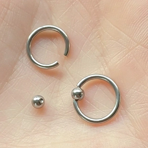 Polished stainless steel captive bead rings set for body piercing held in hand