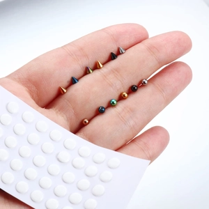 Detailed macro view of multi-colored spike and ball body jewelry held in hand