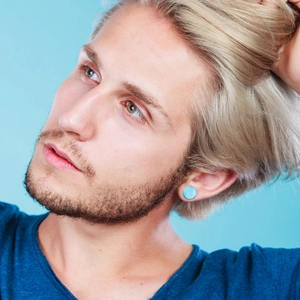 Close-up of a circular sky blue turquoise ear plug jewelry worn by a female model