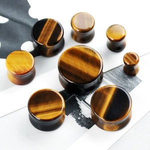 Macro view of Tiger Eye stone ear plugs in various sizes with natural brown cat-eye texture