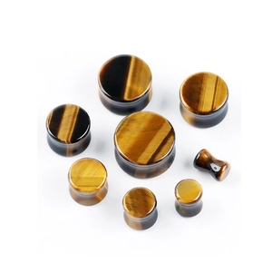 Macro detail of seven tiger eye stone ear plugs with natural golden silk texture