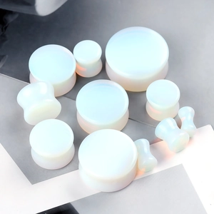 Macro view of opal stone ear gauges in various sizes with a smooth iridescent finish