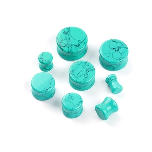 Macro detail of turquoise style ear plug gauges with black marble texture on white background