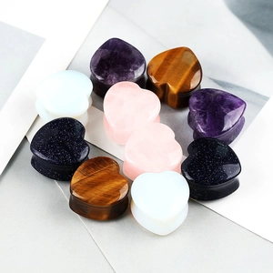 Detailed view of heart-shaped stone ear gauges in amethyst, quartz, and tiger eye stones