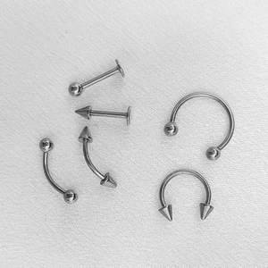 Dettaglio del set di piercing in acciaio inossidabile argento con sfere e coni