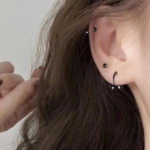 Vista dettagliata di un set di 12 piercing neri in acciaio inossidabile con ferro di cavallo