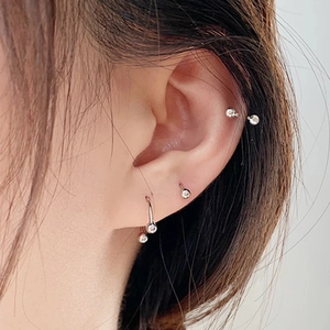 Primo piano di un set di piercing in acciaio argentato con borchie e gioielli a ferro di cavallo