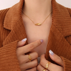 Minimalist gold twisted tube pendant necklace on a model with brown corduroy jacket