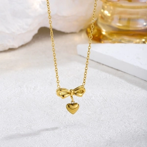 Elegant gold bow and heart pendant necklace with a polished finish and delicate chain