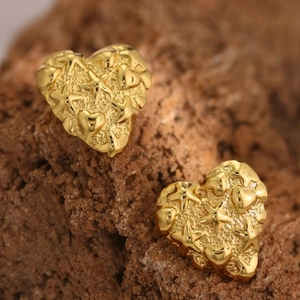 Detailed close-up of golden heart earrings with embossed starfish and matte texture