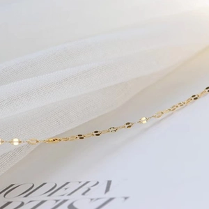 Detailed macro shot of 18k gold-plated titanium steel chain on white tulle background