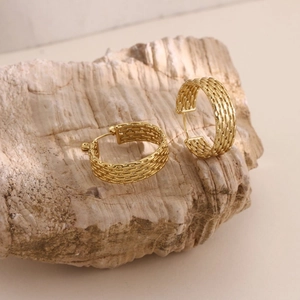 Detailed close-up of gold 18k plated textured hoop earrings on a natural stone base