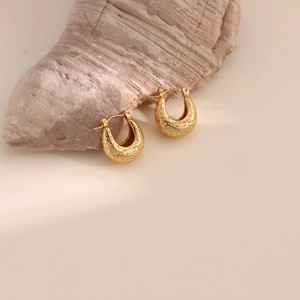 Detailed close-up of gold-plated stainless steel earrings with irregular lava texture