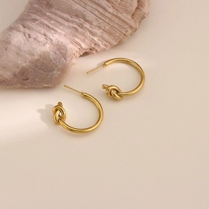 Detail of 18k gold plated stainless steel hoop earrings with a decorative central knot element