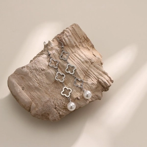 Boucles d'oreilles trèfle ajouré argenté avec perles blanches sur un support en pierre