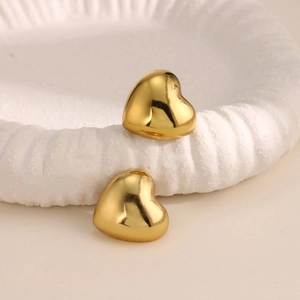 Pendientes de botón de corazón 3D dorados en un plato de cerámica texturizado