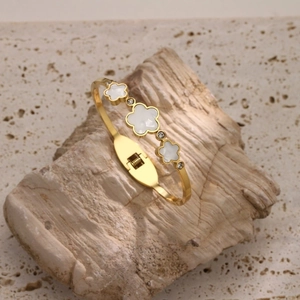 Detail of gold titanium steel bangle with shell flower charms and zircon stones