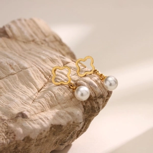 Elegantes pendientes de trébol dorado con perla blanca sobre base de piedra natural