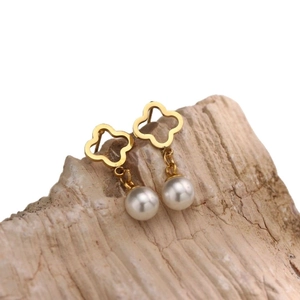 Pendientes de trébol dorado con perlas blancas sobre una base de piedra natural