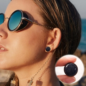 Close-up of blue sandstone ear gauge with starry texture worn in a lifestyle setting