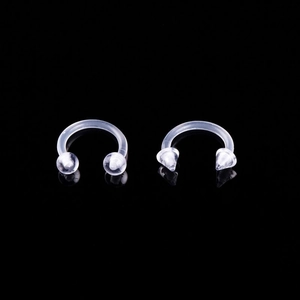 Macro view of transparent acrylic horseshoe piercings with ball and cone ends on black background