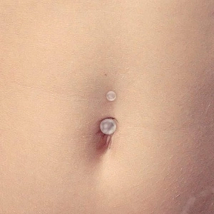 Macro shot of a transparent acrylic belly button ring with double ball design on skin