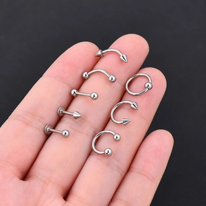 Set de 7 piercings de acero inoxidable con bolas y conos sobre mano con fondo negro sólido