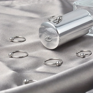 Set de anillos con bola cautiva de acero inoxidable sobre un fondo de satén gris