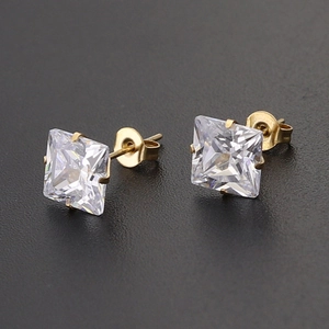 Detailed close-up of golden square-cut zircon stud earrings with classic 4-prong setting