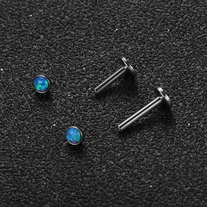 Vista macro de piercings labret de acero inoxidable con piedras de opale azul verdoso