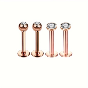 Détail de quatre piercings de lèvre en acier inoxydable rose doré avec zircons