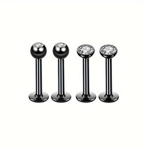 Détail macro de quatre piercings de lèvre noirs en acier avec pierres de zircon