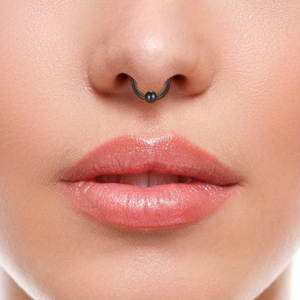 Detailopname van een zwarte hoefijzer septum ring met metalen kraal op de neus