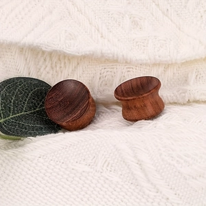 Gros plan d'écarteurs d'oreilles en bois naturel avec design à double évasement