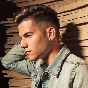 Gros plan d'une boucle d'oreille pendante en acier noir portée par un modèle masculin