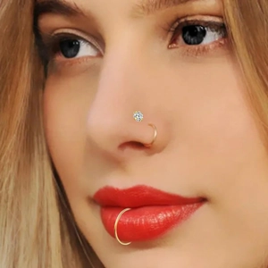 Primer plano de piercings de nariz y aros dorados en una modelo para joyas de cuerpo