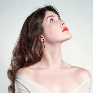 Gros plan de boucles d'oreilles créoles croix en acier noir sur un modèle féminin
