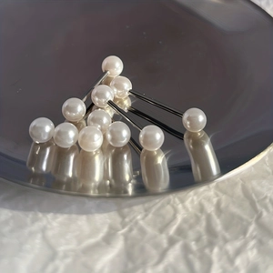 Vue détaillée de piercings en acier inoxydable avec perles blanches sur plateau argenté