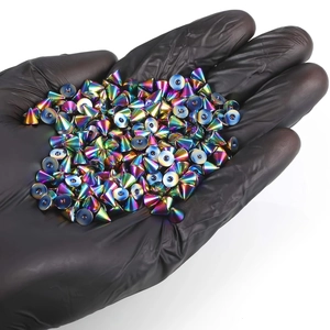 Pointes de piercing irisées en acier inoxydable présentées dans une main gantée de noir