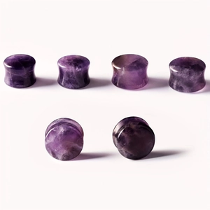 Macro shot of natural amethyst ear plugs with smooth saddle design and purple stone texture