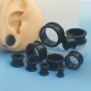 Detail view of black silicone ear gauges in various sizes with a realistic ear display model