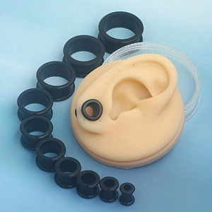 12-piece black silicone ear stretching kit with different sizes on blue background