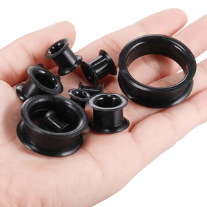 Set of flexible black silicone ear tunnels in multiple sizes held in a palm for scale