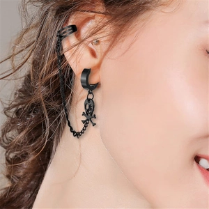 Detail eines schwarzen Punk-Ohrrings mit Totenkopf-Anhänger, Kette und Ohrklemme am Ohr