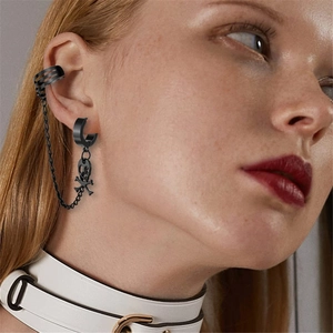 Detail von schwarzem Punk-Ohrclip und Stecker mit Kette und Totenkopf-Anhänger am Model